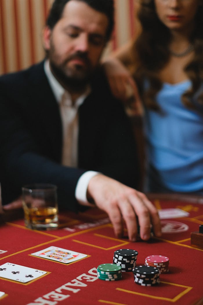 Close-up of a man playing poker with chips and cards on a casino table indoors.